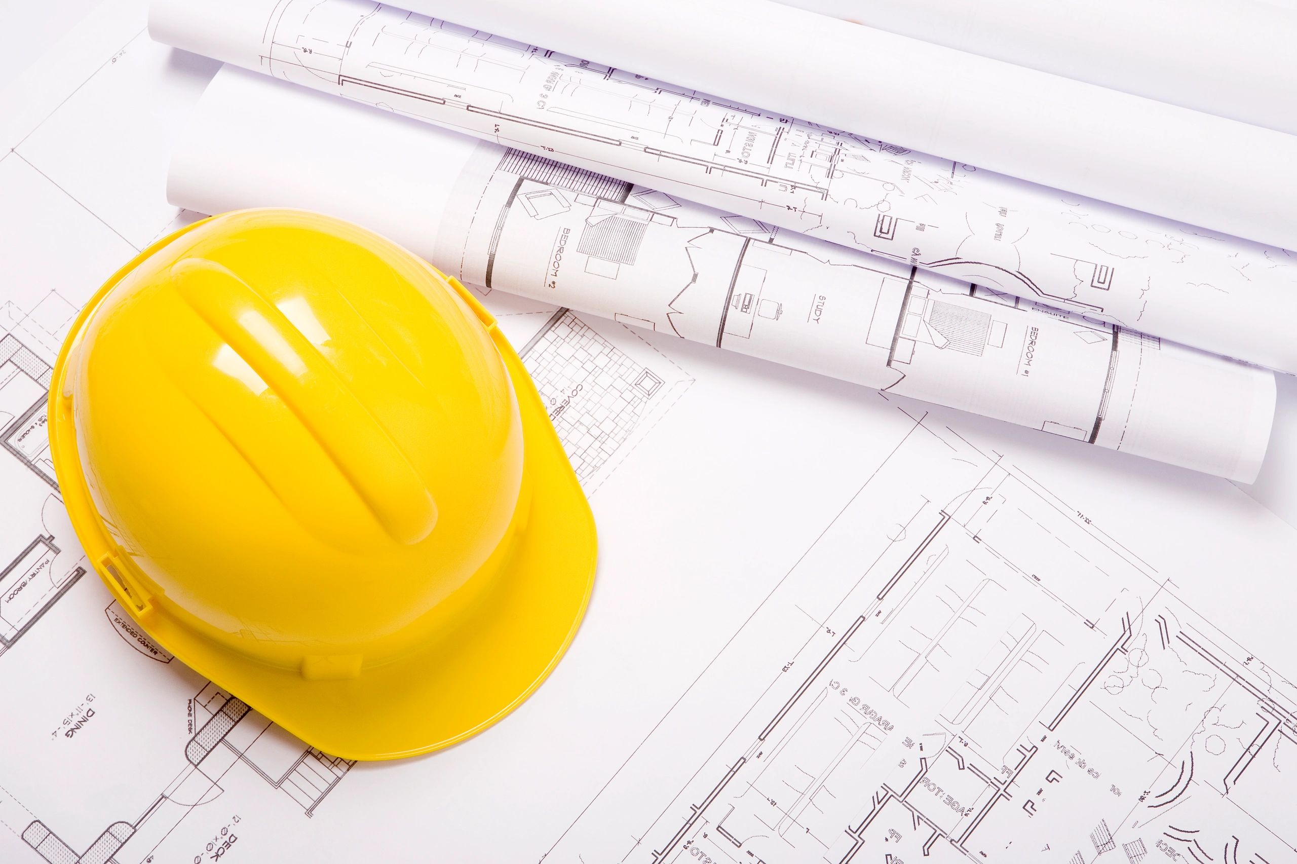 Hard hat and architectural plans representing preconstruction planning.